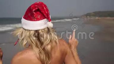 <strong>美</strong>丽的女人穿着<strong>圣诞</strong>老人的服装在海滩上跳舞。 海上热带地区的<strong>新年</strong>和<strong>圣诞</strong>节