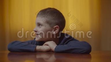 自闭症男孩坐在办公桌前表现情绪的肖像。 有自闭症的孩子在家里笑得开心