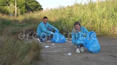 两名青年<strong>志愿者在</strong>河岸捡垃圾。 志愿人员概念。