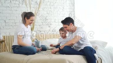 怀孕夫妇与儿子在床上玩牌游戏