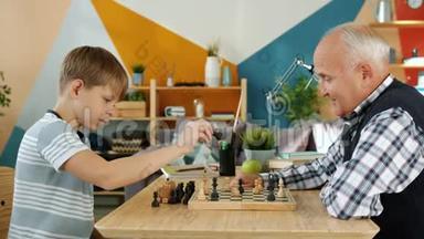 老人和有趣的孙子在家下棋，在家玩着击掌大笑