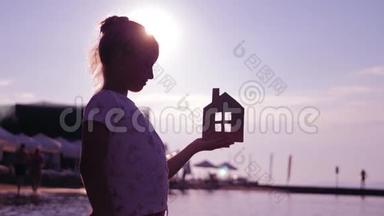 日落时，女孩在<strong>海</strong>滩上拿着纸房子。 人，梦想，家庭，<strong>房地产</strong>和家居理念.. 儿童梦