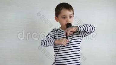 一个小男孩手里拿着麦克风，唱着一首歌，扮演歌手。 孩子<strong>体验</strong>快乐的情绪