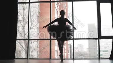 剪影。 芭蕾舞演员穿着黑色的芭蕾舞裙在城市的背景上跳舞。 穿着尖头鞋的美丽芭蕾。 天鹅的形象