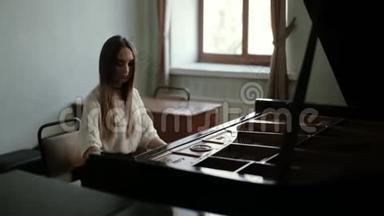 一位年轻的钢琴家，长发在窗户附近的大钢琴上弹奏音乐