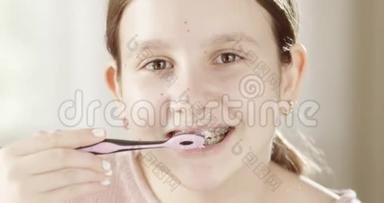 可爱的女孩用牙套刷牙，用牙刷看着相机，口腔科，口腔科，正畸保健科