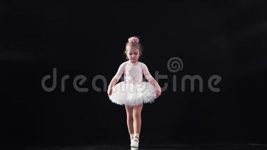 穿着粉红色芭蕾舞裙的儿童芭蕾舞演员在舞台上背光跳舞。 孩子们`芭蕾。 慢动作。