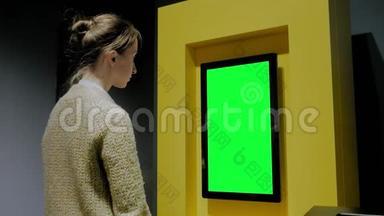 在展览中看到空白绿色<strong>展示墙</strong>的女人-绿色屏幕概念