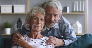 可爱的老丈夫<strong>拥</strong>抱<strong>坐</strong>在沙发上微笑的老女人。