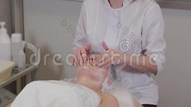 一位<strong>专业</strong>的<strong>美容师</strong>用液体肥皂`病人的脸上同时按摩。