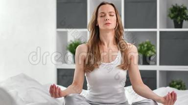 放松的女人坐在床上的莲花姿势冥想。 拍摄红鸦4k影院