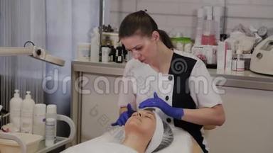 <strong>专业美容师</strong>用擦洗油涂在女人的脸上，用她的手按摩。