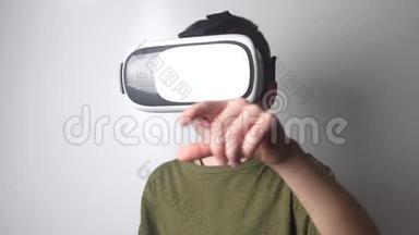 男孩在白色背景上使用虚拟现实耳机头盔。 虚拟现实。 虚拟现实眼镜。 新的高科技技术..