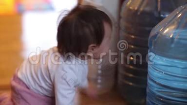 小女孩坐在尿布里，拿着一<strong>大</strong>瓶饮用水，微笑着给五个张开的手标志。