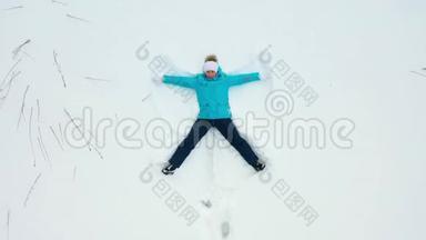 一个女孩在森林<strong>的</strong>空地上做一个<strong>雪天</strong>使<strong>的</strong>身影。 一个女孩躺在雪地里<strong>的</strong>空中摄影。