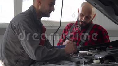 两名专业机械师在<strong>汽车</strong>修理厂修理一辆<strong>汽车</strong>。 <strong>汽车</strong>服务、维修和保养
