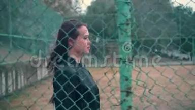 漂亮而热情的女孩穿着铁栅栏后面的自行车夹克。 被关在<strong>监狱</strong>里的年轻女子锁着金属栅栏。