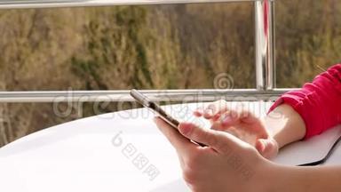 特写双手，少年少女使用智能手机，在开放式阳台上.. 春天阳光明媚的一天。