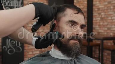 在理发店用理发机和梳子<strong>剪头</strong>发的留着胡子的人。 理发师用发型