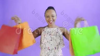 一位非洲裔美国妇女的画像在摄影棚里用<strong>紫色</strong>背景的<strong>购</strong>物袋跳舞。幸福女人抱