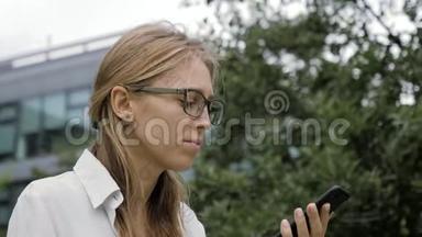 戴眼镜的妇女在户外使用智能<strong>手机</strong>语音识别<strong>功能</strong>。