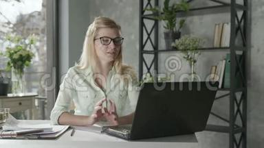 女<strong>企业</strong>家讨论<strong>视频</strong>电话与商业伙伴坐在桌子旁，笔记本电脑旁边