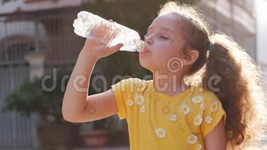 可爱的女孩解渴，从房子附近的街道上的一个塑料瓶里喝。 慢动作小女孩急切地