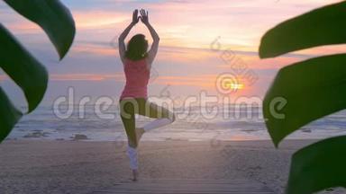 在夏日日落的木步道上做瑜伽的女人