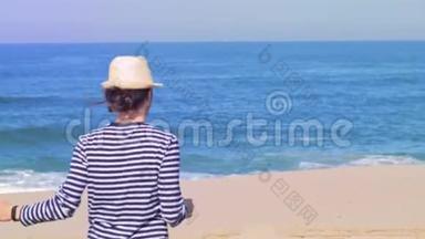 节日旅行时，女人开心地微笑着，双臂向上舞动在海滩上。