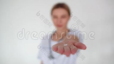 一个拿着药丸的女人的手从镜头里消失了。 女医生手臂上长着一颗药丸，把它捏成拳头然后