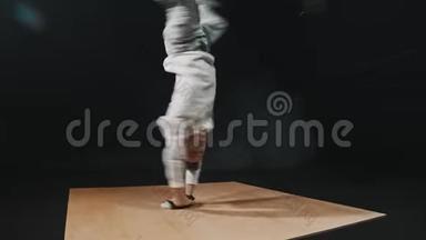 年轻的运动男舞蹈演员在木板上的手上表演一个<strong>跳脱脱</strong>舞的把戏