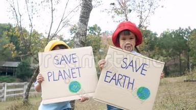 两个小女孩兄弟姐妹抱着`拯救地球`海报显示了抗议森林中塑料污染的标志。