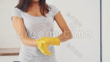 那个女人正在厨房<strong>电饭锅</strong>附近戴上黄色的橡胶手套。 作物。 快关门。 4K.