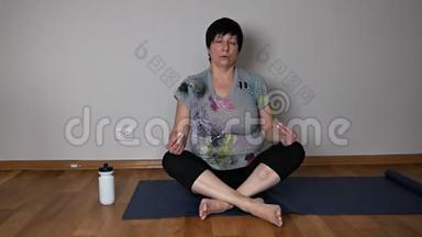 <strong>积极向上的</strong>老年妇女练习瑜伽，呼吸技巧坐在客厅地板上
