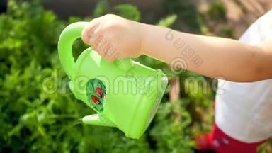 特写4k小男孩用绿色塑料浇水罐在地上浇水的镜头