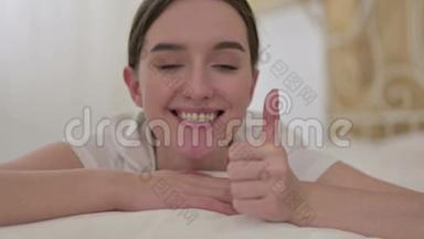 <strong>亲近</strong>快乐的年轻女人，在床上做大拇指