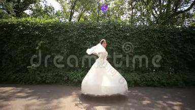 快乐的新娘在公园里旋转。 新娘`礼服。 结婚纪念日。