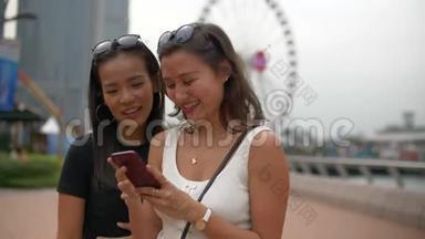 两个年轻的女人在电话里看着有趣的<strong>事情</strong>，在<strong>大</strong>摩天轮上<strong>大</strong>笑