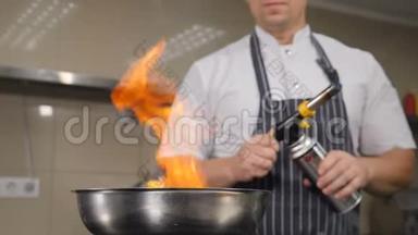 厨师在餐厅厨房做饭。 用火焰烹饪，从煎锅中升起火焰的慢动作镜头。 Hd