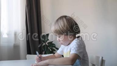 小男孩坐在家里的桌子旁画画，妈妈亲吻拥抱他