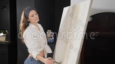 严肃的女艺术家在画油画和在画布上创作抽象的画。 绘画技巧和技巧