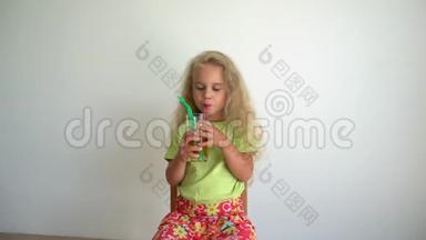 小金发女孩用四根吸管从玻璃杯里喝苹果汁。 万向节运动