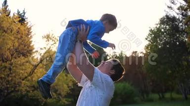 一个年轻的父亲和一个孩子玩，把他抱在怀里，吐了<strong>出来</strong>。 <strong>太阳</strong>`阳光透过孩子。 笑声
