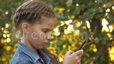 十几岁的女孩独自在<strong>苹果</strong>花园的背景下使用<strong>手机</strong>。 智能<strong>手机</strong>成瘾