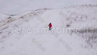 一个孩子走在白色的雪山上，手里拿着雪橇。 冬季运动会。 寒冷的气候条件。 雪山