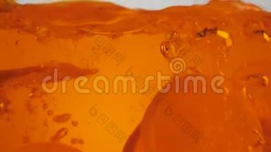 鲜橙片在淡色背景下，随着溅沫和气泡落入橙水或茶中