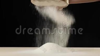 专业的面包师用黑色背景的木筛筛面粉。 掉落的白色颗粒