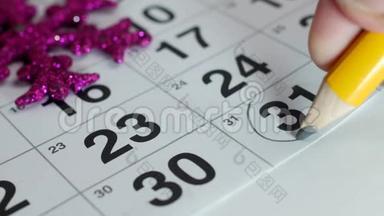 桌子上摆着12月的<strong>年历</strong>，手里拿着一支铅笔，日期是12月31日，特写，新的。