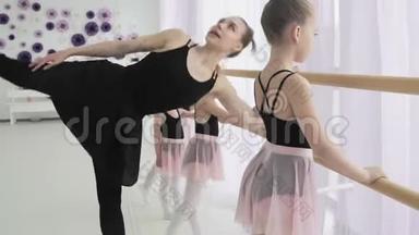 年轻的芭蕾舞演员穿着时髦的芭蕾舞服，在轻盈的舞厅里练习脚动作，穿着木制芭蕾