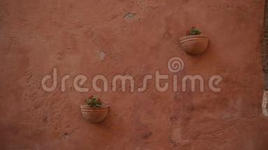两个挂在墙上的陶瓷花盆，红色中提琴，挂在古老的橙色墙上，意大利